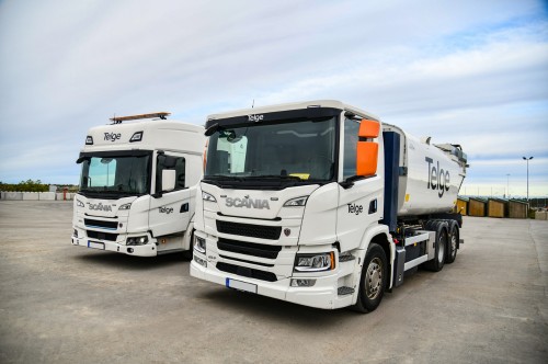 Två vitmålade insamlingsfordon står parkerade på stor asfaltsplan.